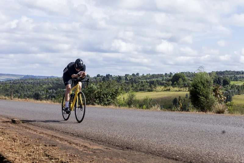 A lone rider on an open road under a wide clouded sky