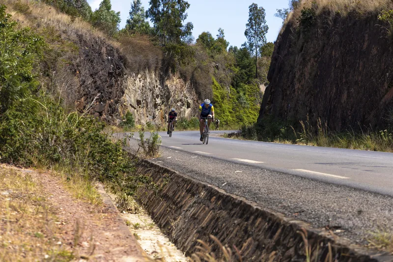 The road cut through a rock face, riders dwarfed by it