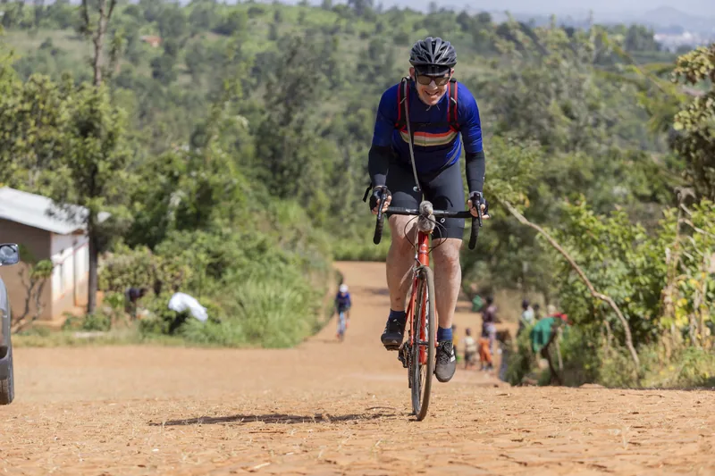 A rider climbing a red dirt road above a village